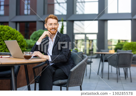 Bearded redhead using laptop at outdoor table in business district Bearded redhead using laptop at outdoor table in business district 130285578