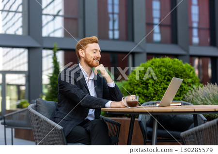 Red-haired businessman having video call on laptop at cafe Red-haired businessman having video call on laptop at cafe 130285579