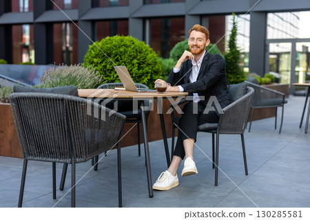 Cheerful man professional posing at outdoor workspace with computer 130285581