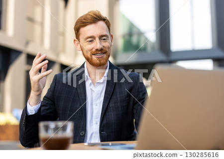 Red-haired man smiling while having video conference 130285616