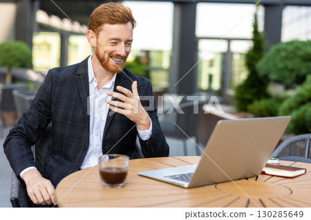 Young businessman in suit on video call at outdoor cafe Young businessman in suit on video call at outdoor cafe 130285649