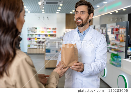 Dark-haired pretty young woman talking to the pharmacist and looking interested Dark-haired pretty young woman talking to the pharmacist and looking interested 130285696