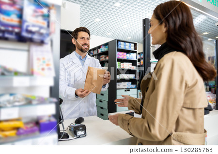 Young dark-haired caucasian woman buying medicines in the pharmacy 130285763