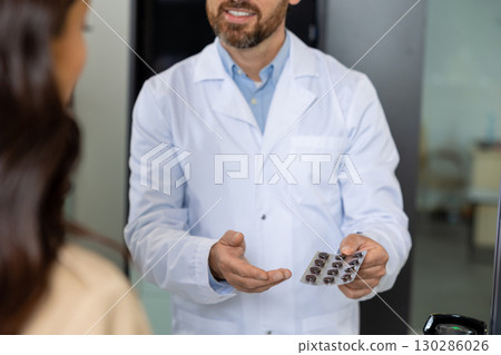 Male pharmacist offering pills to a female client Male pharmacist offering pills to a female client 130286026