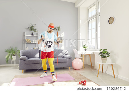 Focused Man In Retro Sportswear Exercising With Resistance Band At Home Focused Man In Retro Sportswear Exercising With Resistance Band At Home 130286742