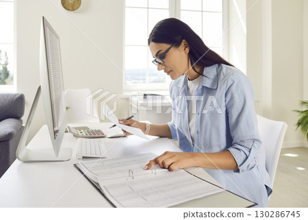 Young business woman accountant working on pc computer with tables at office. 130286745