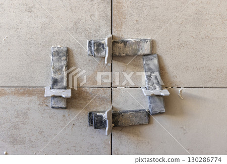 Flat wall tile leveling system. Process of installation of tiles in the bathroom. Home improvement Flat wall tile leveling system. Process of installation of tiles in the bathroom. Home improvement 130286774
