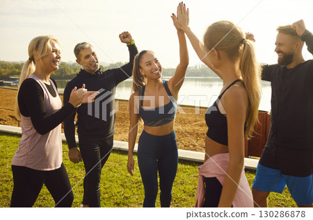 Happy young women giving high five each other rejoicing the success in sport training outdoors. 130286878