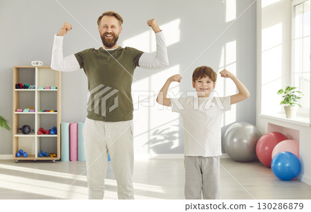 Funny dad and son show off their progress in fitness and show off their muscles in triumphant poses. 130286879