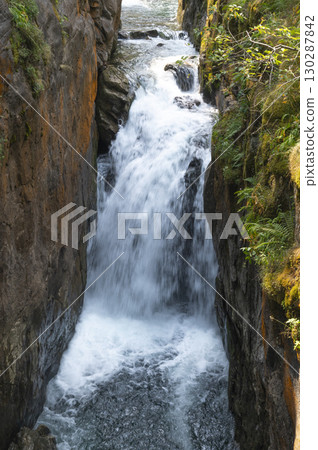 Flowing water cascades through rocky terrain in the Pyrenees near Cauteret, highlighting the beauty 130287842