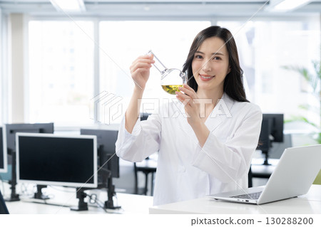 一位身穿白大褂的年輕女研究員在實驗室進行實驗 130288200