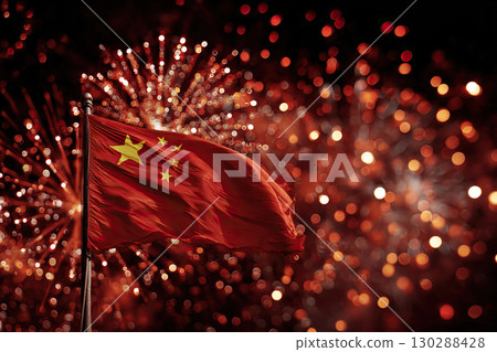 The Chinese flag flutters against the night sky and colorful fireworks explode. The day of celebration of the National Day of the People's Republic of China. 130288428