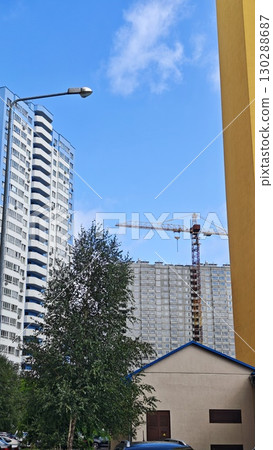 High-rise apartment buildings with a construction crane in the background under a clear blue sky. The image reflects modern urban development and residential infrastructure growth 130288687