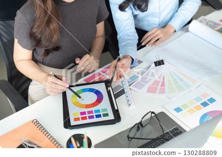 Color Selection. Women architects discussing color schemes and design strategies at a desk. 130288809