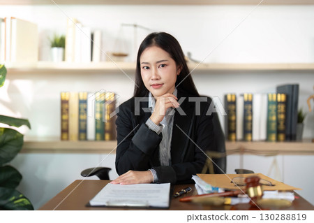 Confident Lawyer. Young female attorney posing in office with legal documents. Confident Lawyer. Young female attorney posing in office with legal documents. 130288819