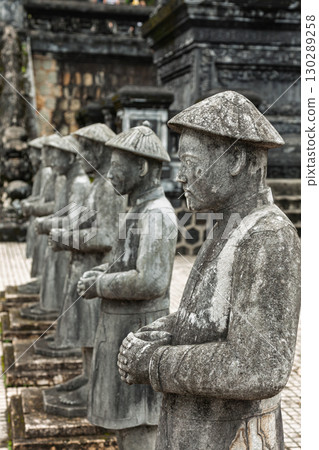 Row of stone royal guard statues wearing traditional hats at Khai Dinh Tomb in Hue Vietnam 130289258