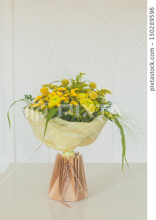 Floral Birthday Gift. Flower bouquet in craft paper bag on white background 130289596