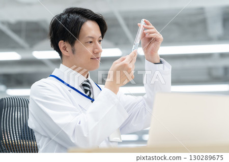 一位身穿白大褂的年輕男研究員在實驗室進行實驗 130289675