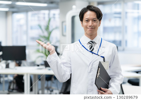 A young male researcher in a white coat conducting an experiment in a laboratory 130289679