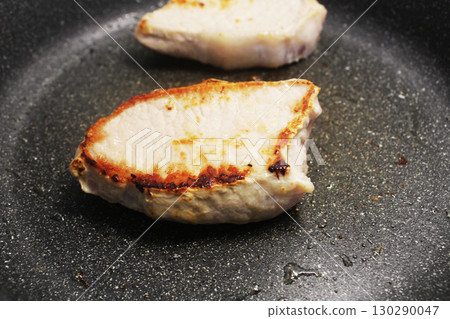 Two pieces of meat frying in a pan close-up 130290047