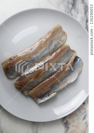 Pieces of herring fillet on a plate View from above. Preparation of fish dishes. horizontal photo Pieces of herring fillet on a plate View from above. Preparation of fish dishes. horizontal photo 130290053
