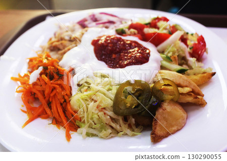 Shawarma on a plate close-up. Vegetables with potatoes and sauce close-up 130290055