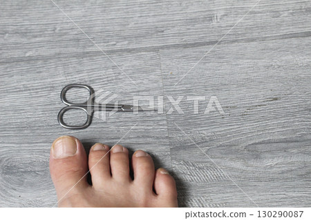 Manicure scissors and foot on a gray background with space for copyspace text 130290087