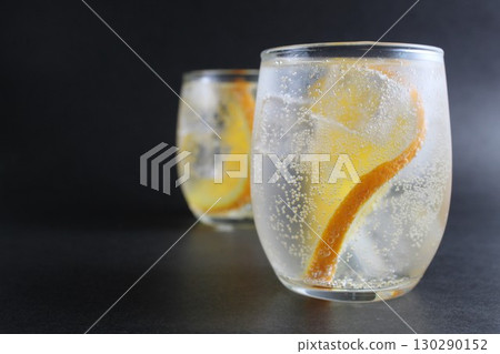 lemonade with orange and ice in a glass on a black background next to lies ice and orange. Summer drink on a black background lemonade with orange and ice in a glass on a black background next to lies ice and orange. Summer drink on a black background 130290152