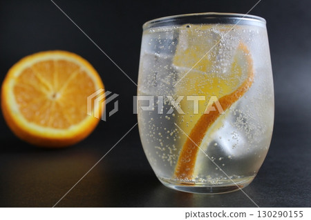 lemonade with orange and ice in a glass on a black background next to lies ice and orange. Summer drink on a black background lemonade with orange and ice in a glass on a black background next to lies ice and orange. Summer drink on a black background 130290155