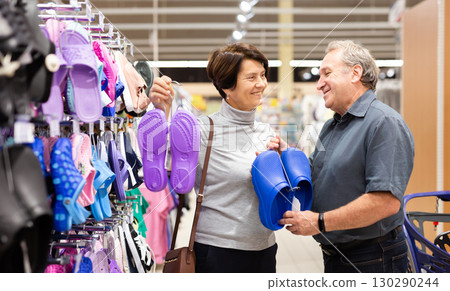 Mature couple choosing slippers in clothes department in grocery store Mature couple choosing slippers in clothes department in grocery store 130290244