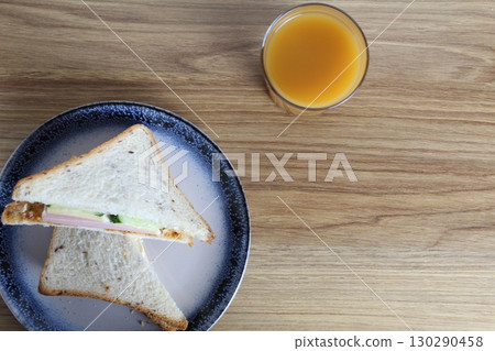 Breakfast snack lunch two sandwiches on a plate and a glass of juice on the table. Kind of super. Flat lay Breakfast snack lunch two sandwiches on a plate and a glass of juice on the table. Kind of super. Flat lay 130290458