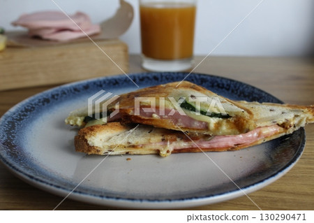 sandwich with ham cheese and vegetable greens close up on a plate next to the juice. Cooking breakfast. Snack sandwich with ham cheese and vegetable greens close up on a plate next to the juice. Cooking breakfast. Snack 130290471