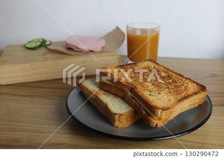 Food, avtrak. Sandwiches with ham cheese and vegetable elenium lie on a gray plate next to the juice of orange apricot on the table. Cooking breakfast Food, avtrak. Sandwiches with ham cheese and vegetable elenium lie on a gray plate next to the juice of orange apricot on the table. Cooking breakfast 130290472