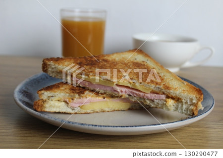 Food, avtrak. Sandwiches with ham cheese and vegetable elenium lie on a gray plate next to the juice of orange apricot on the table. Cooking breakfast 130290477