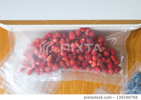 Vacuum sealer of strawberries, honeysuckle in bag, packaging for long-term storage . Vacuum packing machine 130290788
