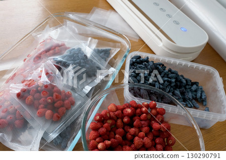Vacuum sealer of strawberries, honeysuckle in bag, packaging for long-term storage . Vacuum packing machine 130290791
