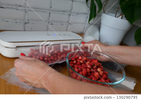 Vacuum sealer of strawberries, honeysuckle in bag, packaging for long-term storage . Vacuum packing machine 130290795