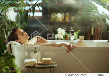Tranquil Woman in a Steamy, Plant-Filled Bath 130290826