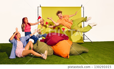 Friends cheering as young man in orange shirt flies into beanbags with dramatic face Friends cheering as young man in orange shirt flies into beanbags with dramatic face 130291015