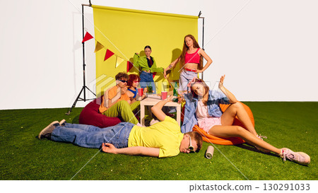 Group of young friends gathered near pizza table with man lying on grass 130291033