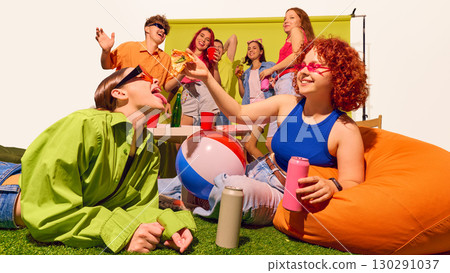 Young woman feeding pizza to friend on grass with group cheering behind 130291037