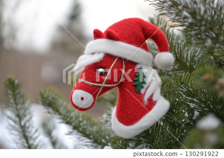 Felt red horse in santa hat. A toy near snow christmas tree 130291922