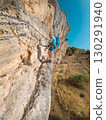 Climber on via ferrata trail, crossing a steep mountain edge 130291940
