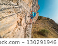 Climber on via ferrata trail, crossing a steep mountain edge 130291946