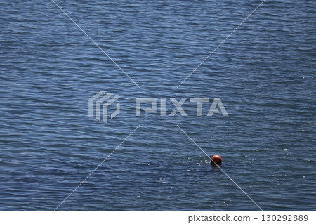 Seascape with orange float on rippling blue sea surface 130292889
