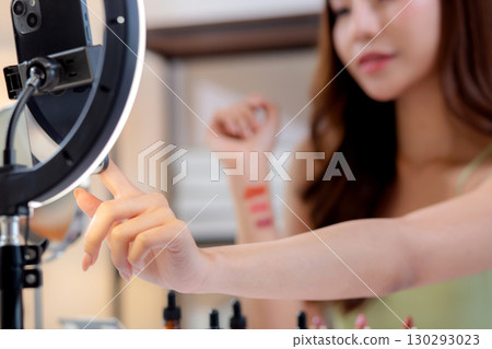 Closeup hands young asian beauty influencer testing multiple lipstick shades on arm. 130293023