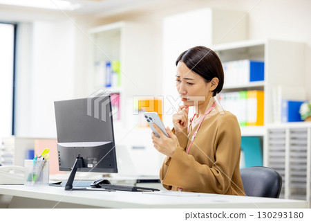 Business woman looking at smartphone and thinking Business woman looking at smartphone and thinking 130293180
