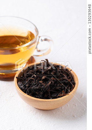 Dried black tea leaves in wooden bowl and hot tea in cup glass  Dried black tea leaves in wooden bowl and hot tea in cup glass  130293648