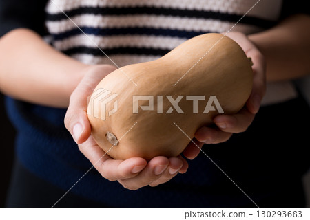 Butternut squash pumpkin holding by woman hand Butternut squash pumpkin holding by woman hand 130293683