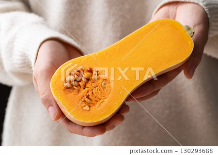 Half butternut squash pumpkin holding by woman hand Half butternut squash pumpkin holding by woman hand 130293688